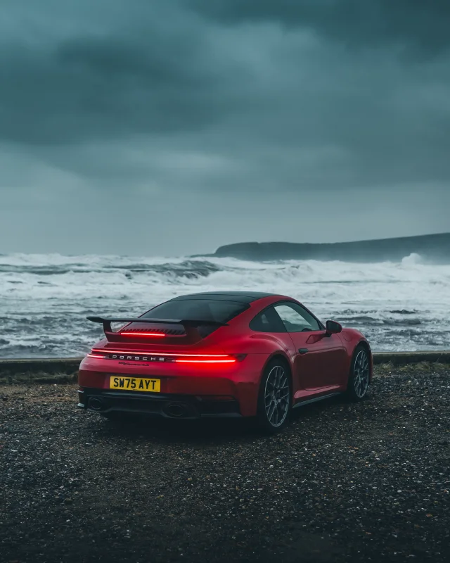 Red Porsche beside a stormy sea