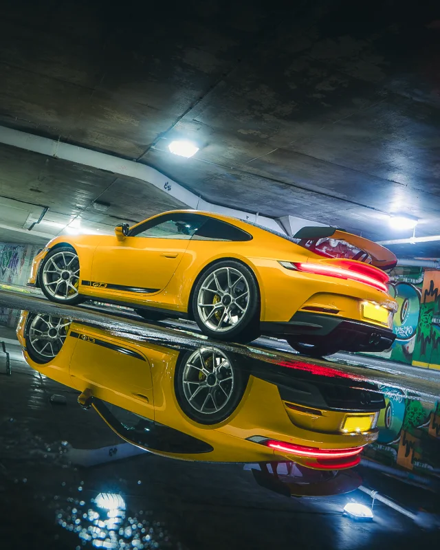 Yellow Porsche GT3 reflected in a puddle